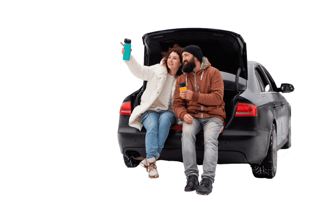 Un couple assis dans le coffre ouvert d'une berline noire prend un selfie